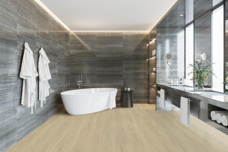 warm toned luxury vinyl flooring in bathroom with white bathtub and stone walls.